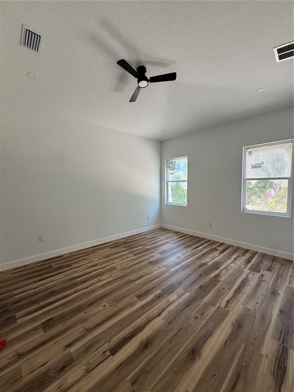 A bedroom features wood-look flooring, a ceiling fan, a sliding glass door, and a window — 611 ELM STREET, SAFETY HARBOR, FL