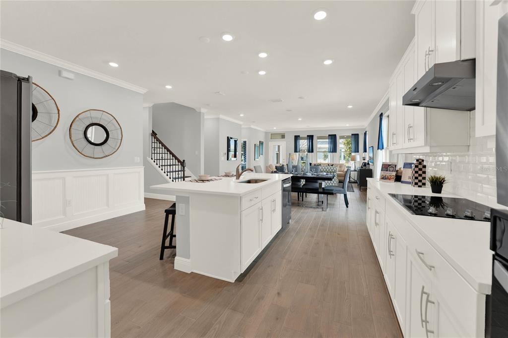 A modern kitchen with white cabinetry, a central island, and wood-look flooring — 11277 HOLLOW BAY DRIVE, WINTER GARDEN, FL