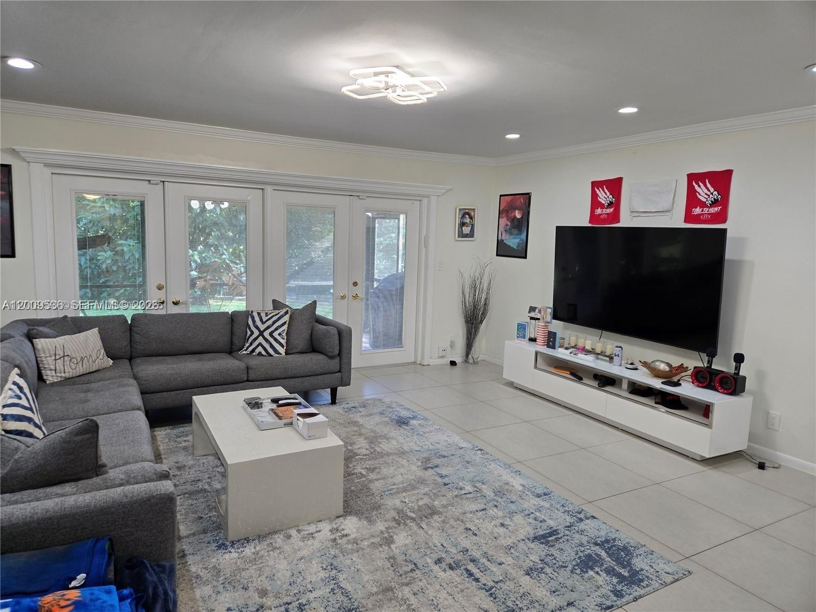 A living room features a grey sectional sofa, a white coffee table, and a wall-mounted television — 295 Jacaranda Dr # 20, Plantation FL 33324, PLANTATION, FL
