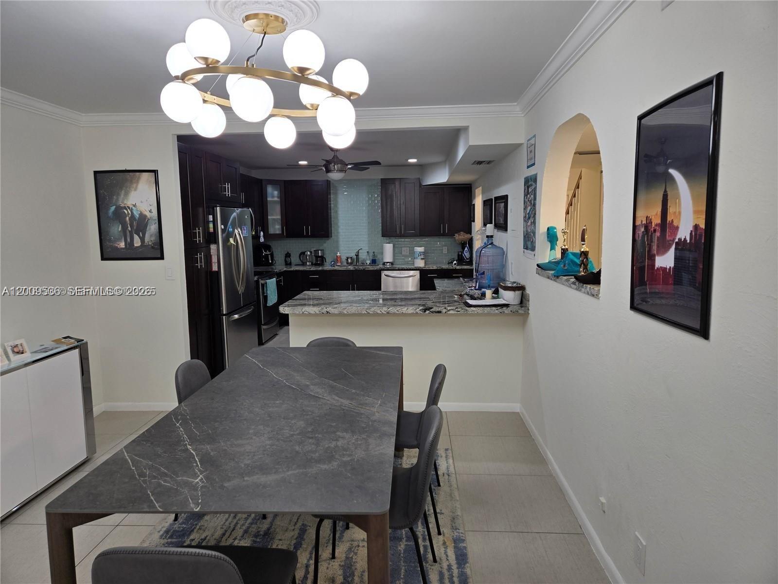 A dining area with a stone table sits before an open kitchen with dark cabinets — 295 Jacaranda Dr # 20, Plantation FL 33324, PLANTATION, FL