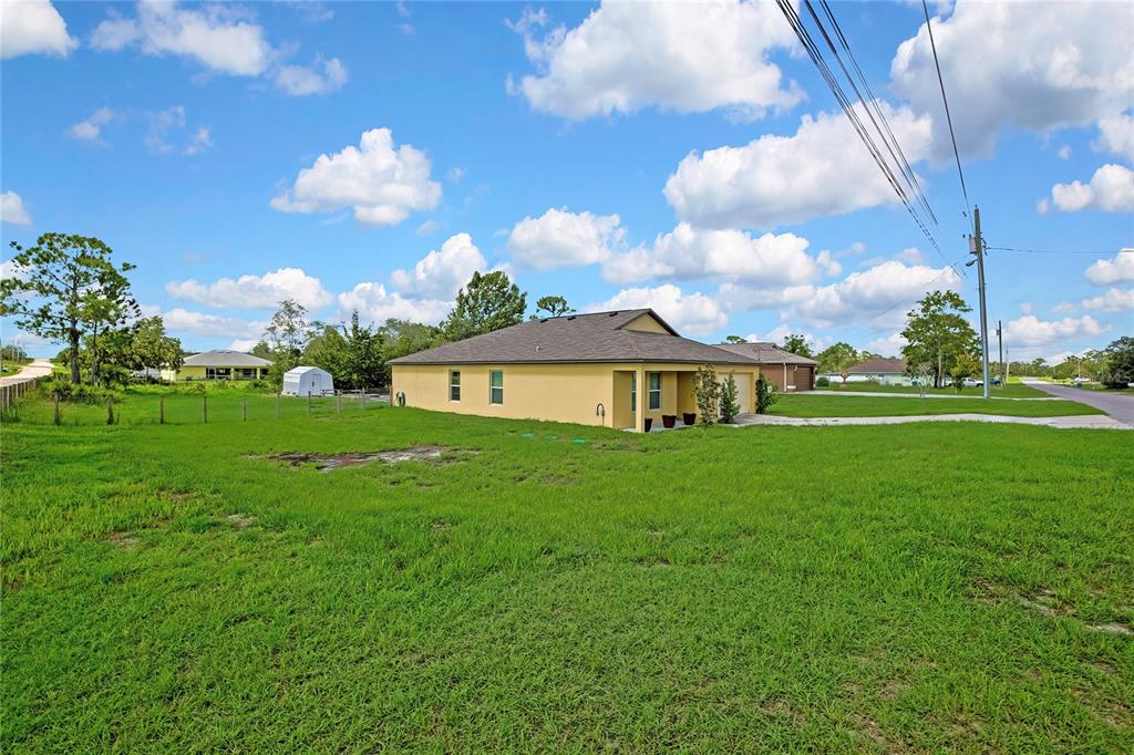 A yellow single-story house with a garage sits on a large, grassy residential lot — 13134 OSPREY AVENUE, WEEKI WACHEE, FL