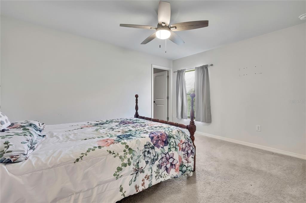 A bedroom features a floral bedspread, a ceiling fan, and a window with gray curtains — 13134 OSPREY AVENUE, WEEKI WACHEE, FL