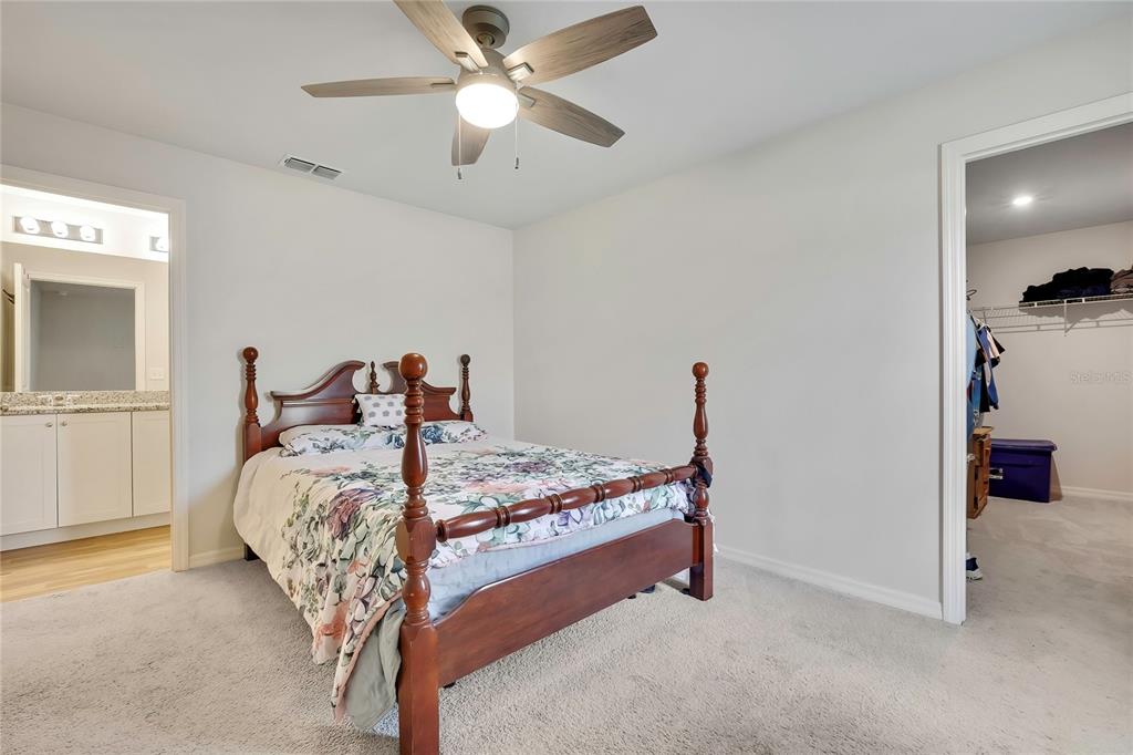 A bedroom features a wooden four-poster bed, carpeted flooring, a ceiling fan, and an attached bathroom — 13134 OSPREY AVENUE, WEEKI WACHEE, FL