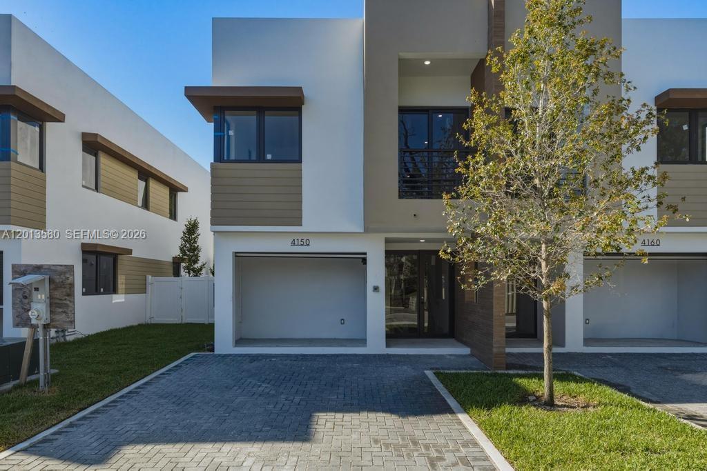 A modern two-story townhouse features a paved driveway, a garage, and a small front lawn — 4120 S Oak Pl, Dania Beach FL 33314, DANIA BEACH, FL