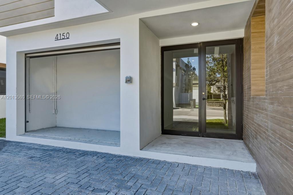 A modern home entrance features a covered parking area, a glass door, and wood-look siding — 4120 S Oak Pl, Dania Beach FL 33314, DANIA BEACH, FL