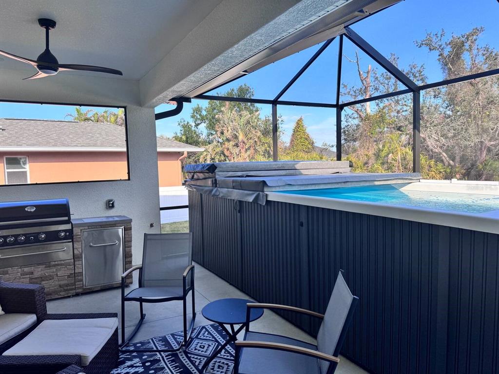 A covered patio features an outdoor grill, seating area, and an above-ground swim spa — 26 MEDALIST WAY, ROTONDA WEST, FL
