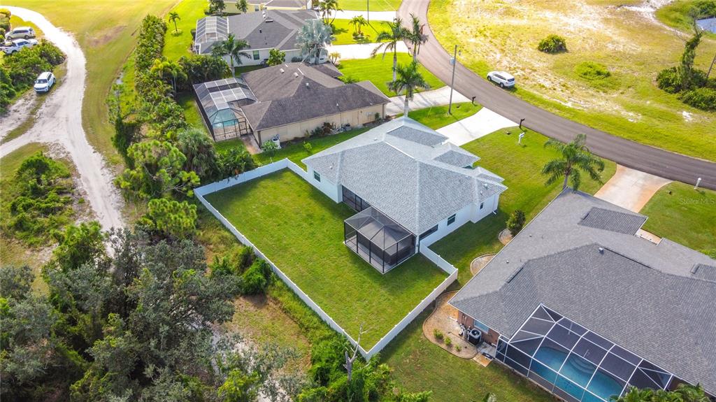 An aerial view shows a suburban house with a fenced backyard and a screened lanai — 26 MEDALIST WAY, ROTONDA WEST, FL