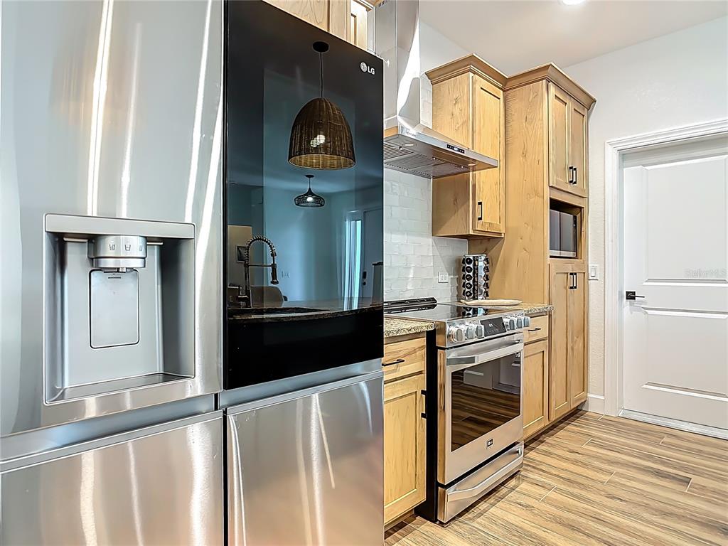 A kitchen features stainless steel appliances, light wood cabinetry, and wood-look tile flooring — 26 MEDALIST WAY, ROTONDA WEST, FL
