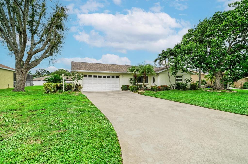 A single-story house with a white garage door and a concrete driveway under a blue sky — 4723 PALM AIRE CIRCLE, SARASOTA, FL