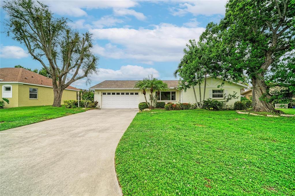 A single-story house with a white garage, light-colored siding, and a large front lawn — 4723 PALM AIRE CIRCLE, SARASOTA, FL