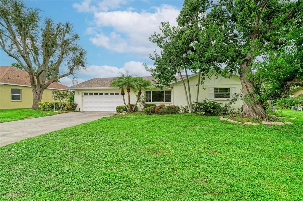 A single-story house with a white garage, light-colored stucco exterior, and large trees in front — 4723 PALM AIRE CIRCLE, SARASOTA, FL