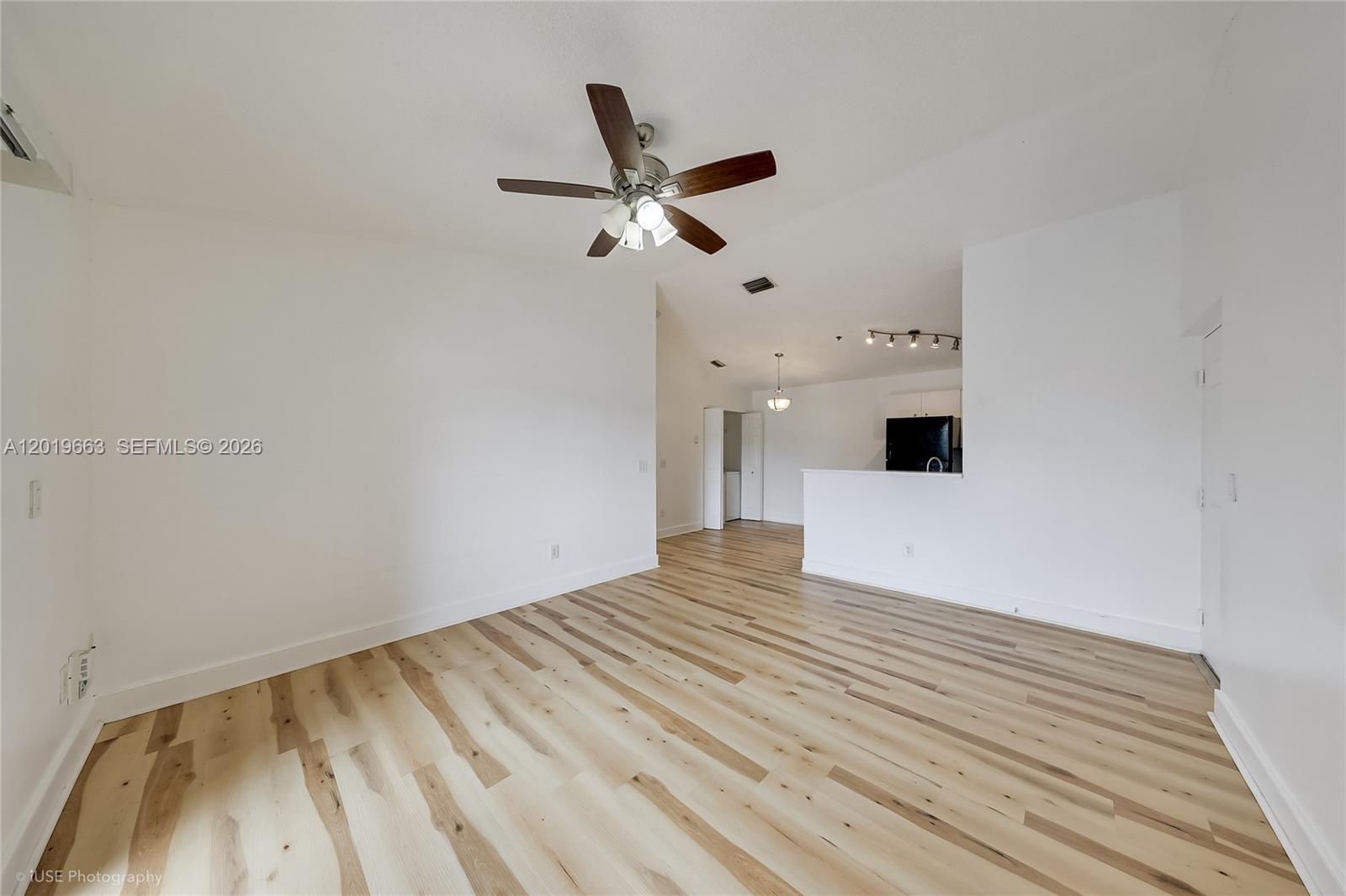 An empty living area features light wood-look flooring, white walls, and a ceiling fan — 5570 NW 61st St # 930, Coconut Creek FL 33073, COCONUT CREEK, FL