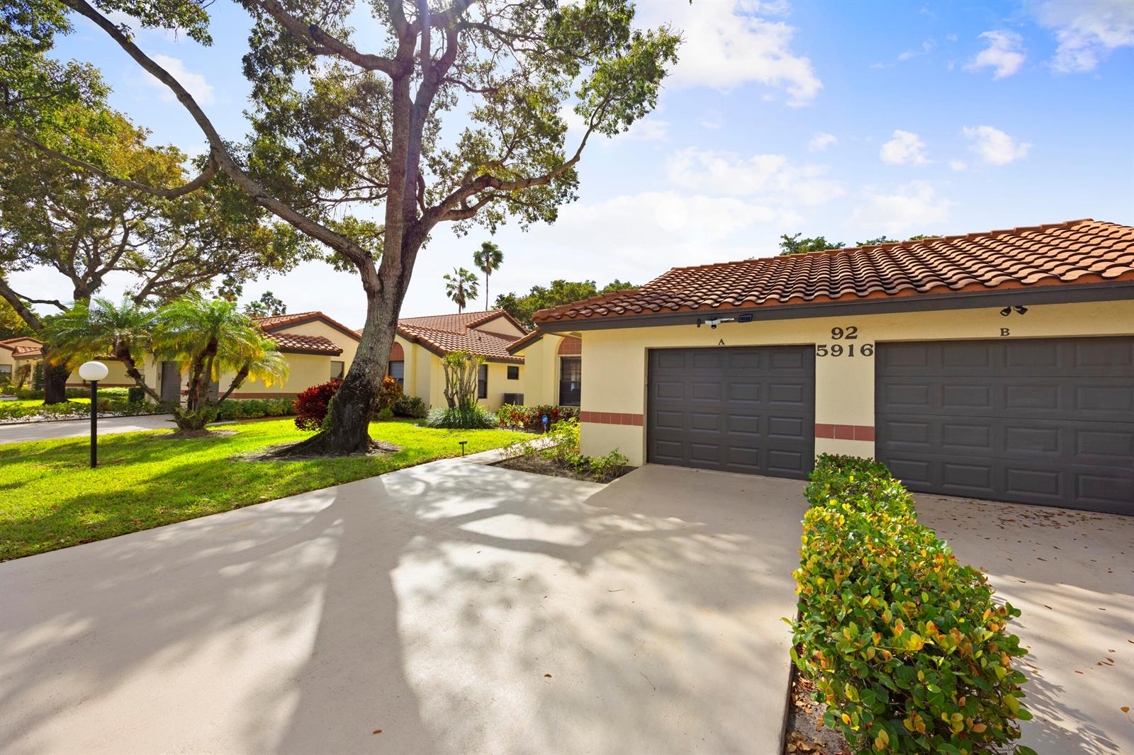 A view of a single-story residential building with two garage doors and a concrete driveway — 5916 Sunswept Lane # A, Boynton Beach FL 33437, BOYNTON BEACH, FL