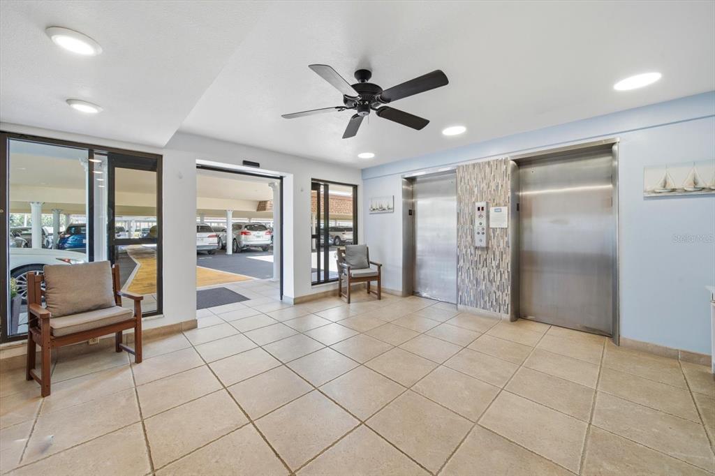 A lobby area features tile flooring, two elevators, a ceiling fan, and two wooden chairs — 5108 BRITTANY DRIVE S UNIT 607, ST PETERSBURG, FL