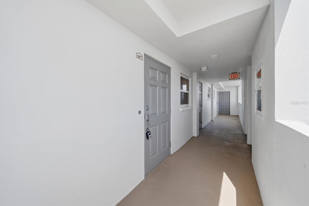 A gray door labeled 607 sits in a white hallway with an exit sign — 5108 BRITTANY DRIVE S UNIT 607, ST PETERSBURG, FL