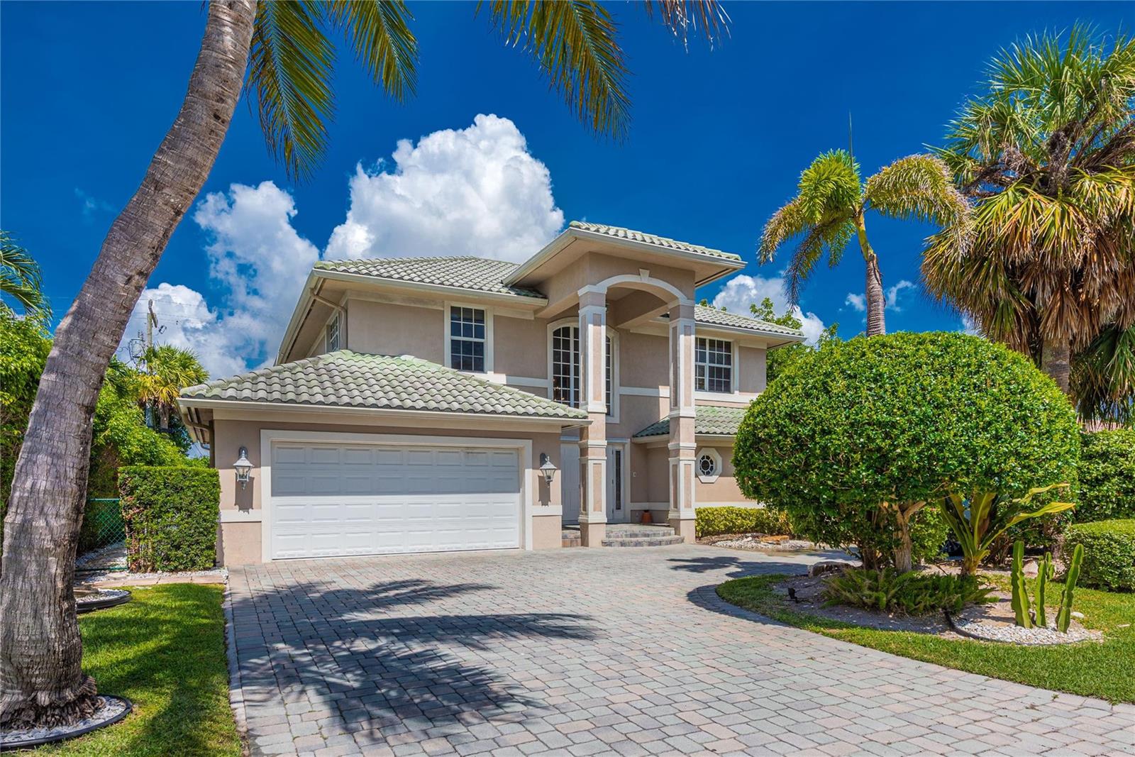 A two-story house with a beige stucco exterior, green tile roof, and a paved driveway — 2999 Banyan Road, Boca Raton FL 33432, BOCA RATON, FL