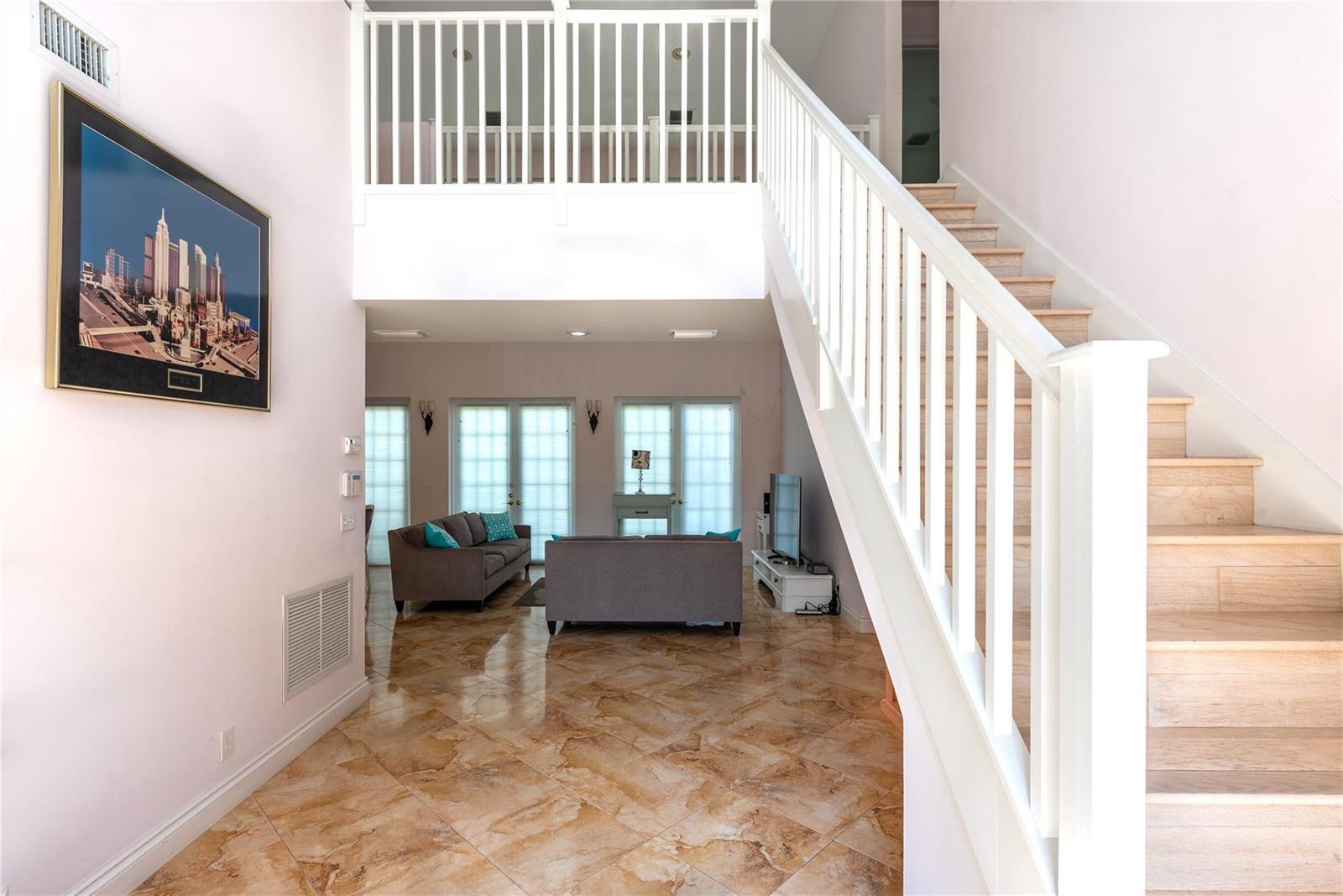 A foyer with marble tile floors leads to a living room and a wooden staircase — 2999 Banyan Road, Boca Raton FL 33432, BOCA RATON, FL