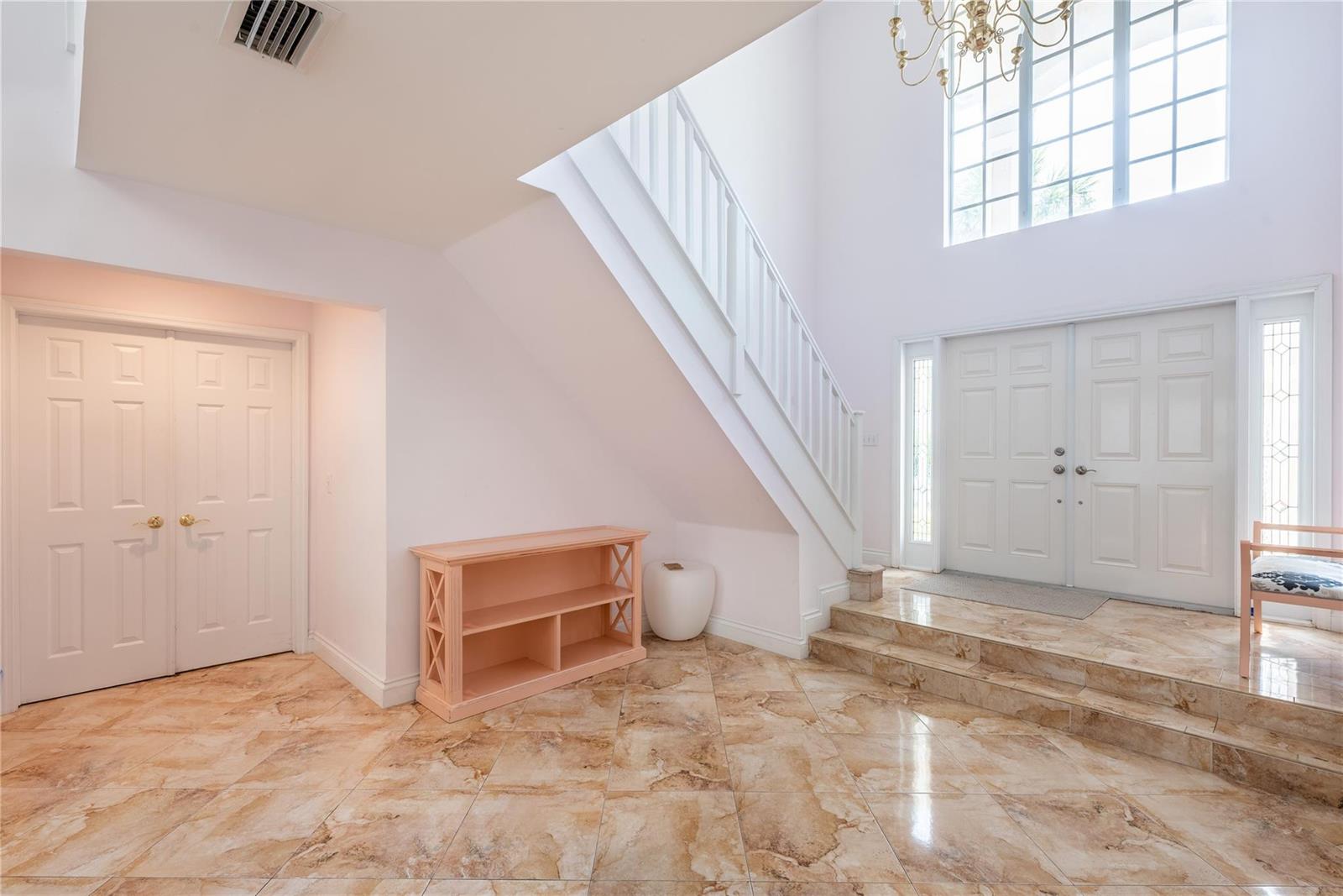 A bright foyer features a staircase, double front doors, and light-colored marble tile flooring — 2999 Banyan Road, Boca Raton FL 33432, BOCA RATON, FL