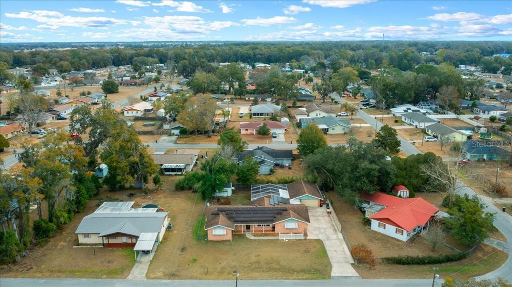 An aerial view shows a residential neighborhood with several single-story houses and surrounding trees — 10629 SE 51ST AVENUE, BELLEVIEW, FL