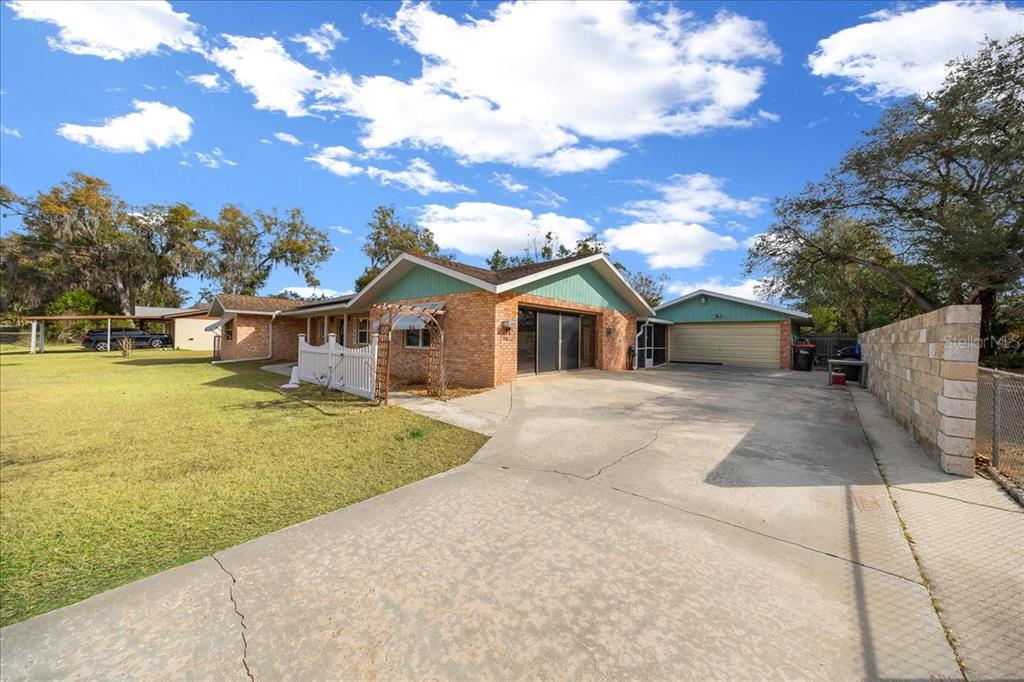 A single-story brick house with a teal gable, attached garage, and a large concrete driveway — 10629 SE 51ST AVENUE, BELLEVIEW, FL
