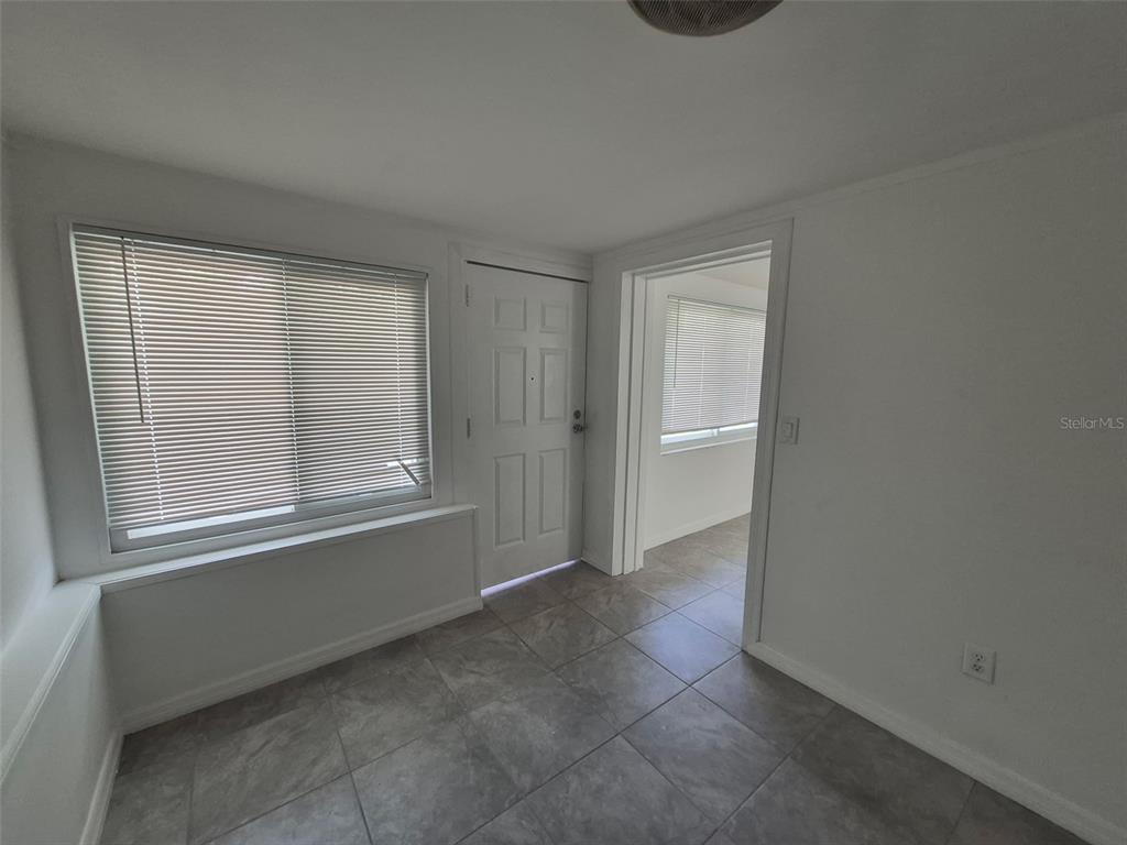 A room with gray tile flooring, a window with blinds, and a white door — 27 E LEMON STREET, BEVERLY HILLS, FL