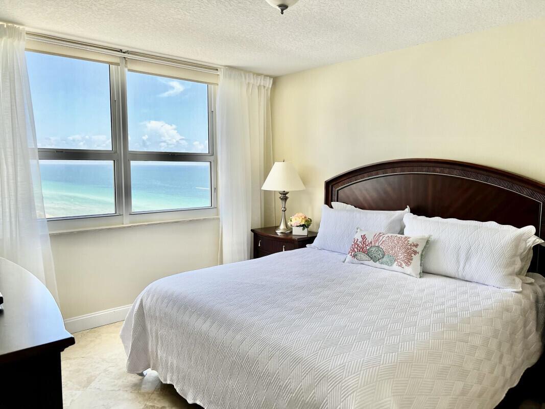 A bedroom features a queen bed, a dark wood headboard, and a window overlooking the ocean — 2080 S Ocean Drive # 1608, Hallandale Beach FL 33009, HALLANDALE BEACH, FL