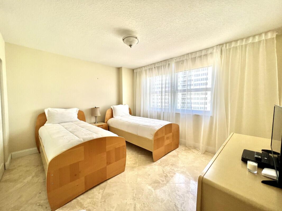 A bedroom features two twin beds with wooden frames, white bedding, and light tile flooring — 2080 S Ocean Drive # 1608, Hallandale Beach FL 33009, HALLANDALE BEACH, FL