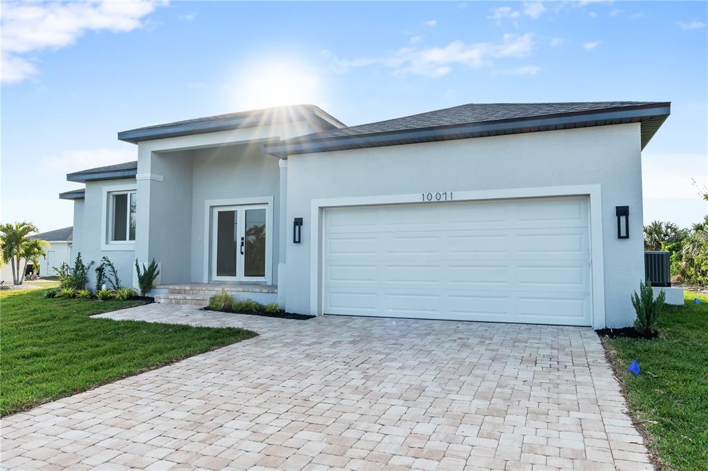A single-story house with a white stucco exterior, a two-car garage, and a paver driveway — 10071 KINGSVILLE DRIVE, PORT CHARLOTTE, FL