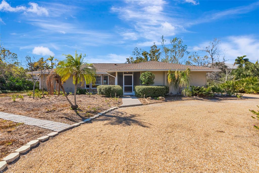 A single-story house with a gravel driveway, palm trees, and a concrete walkway — 950 OXFORD DRIVE, ENGLEWOOD, FL