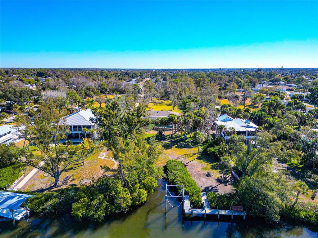 An aerial view shows two waterfront houses with docks and lush trees along a canal — 950 OXFORD DRIVE, ENGLEWOOD, FL