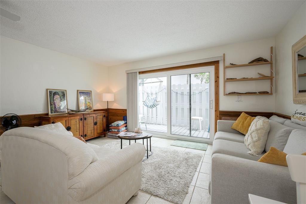 A living room features a white sofa, nested coffee tables, and wood wainscoting on walls — 4786 S ATLANTIC AVENUE UNIT B1, PONCE INLET, FL