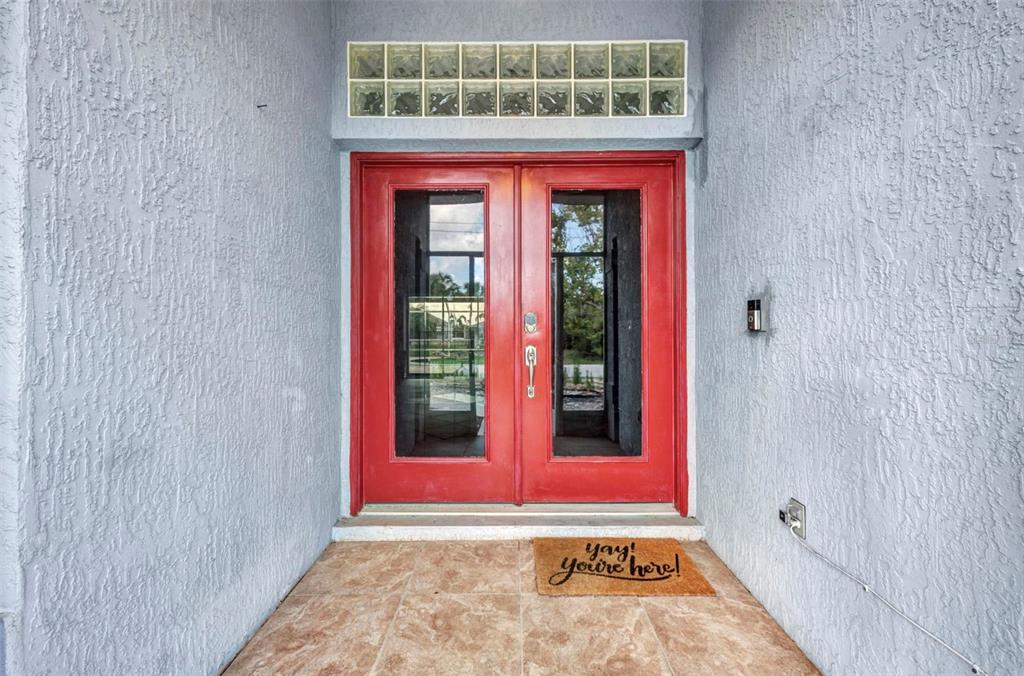 A red double front door with glass panels sits under a glass block transom window — 9582 ARSIPE CIRCLE, PORT CHARLOTTE, FL