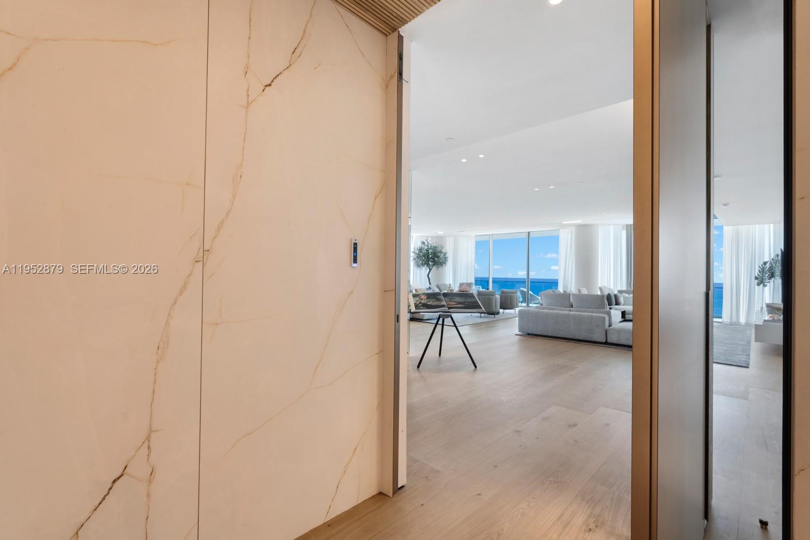 A view through a doorway reveals a bright living room with ocean views and flooring — 10203 Collins Ave # 2701, Bal Harbour FL 33154, BAL HARBOUR, FL