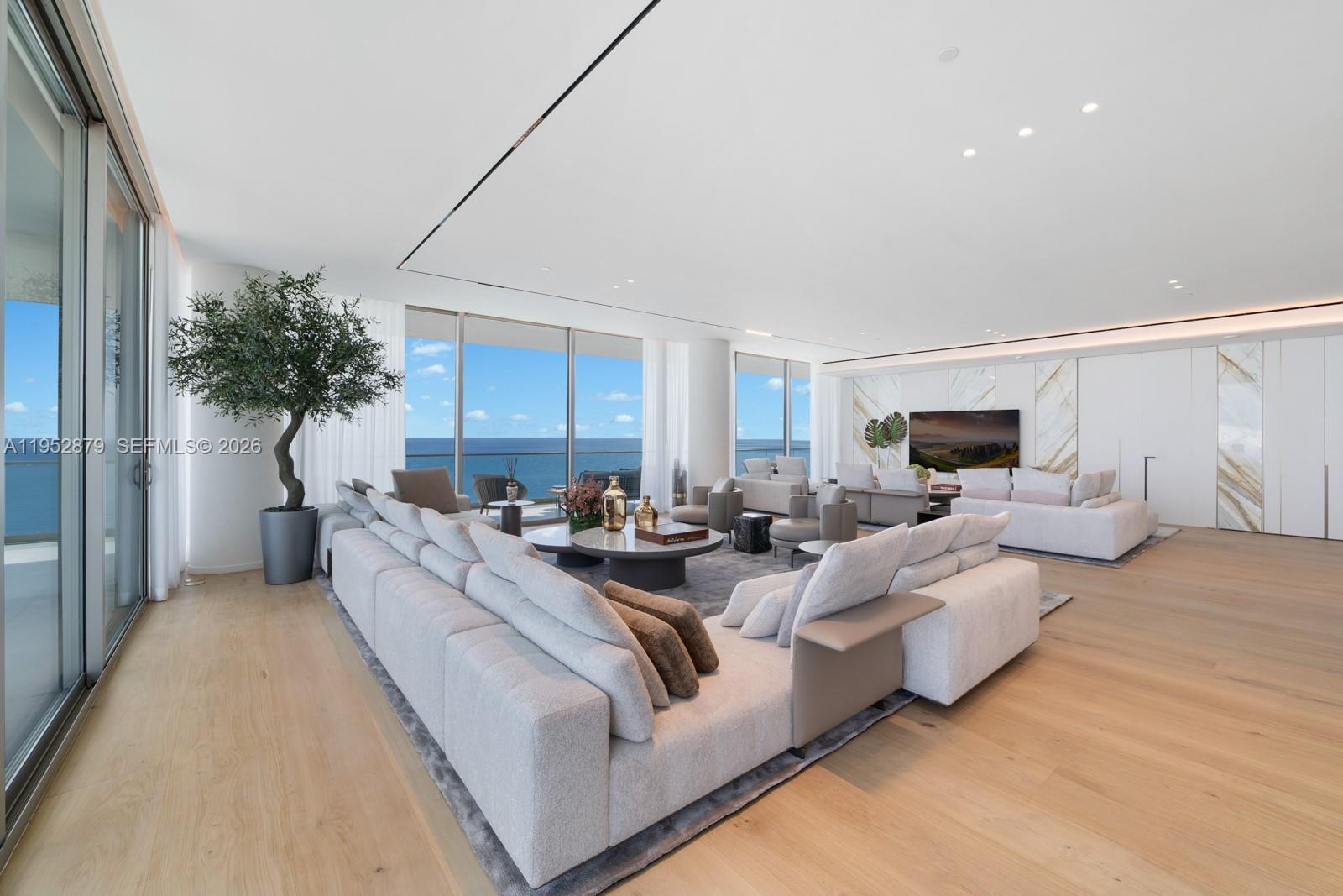 A spacious living room features light wood floors, large sofas, and floor-to-ceiling ocean views — 10203 Collins Ave # 2701, Bal Harbour FL 33154, BAL HARBOUR, FL