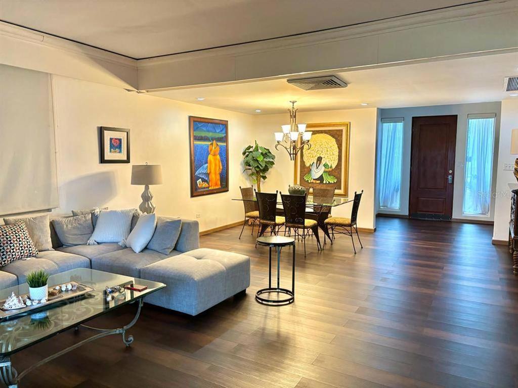 A living and dining area features a gray sectional sofa, glass tables, and dark wood flooring — 22 FAIRWAYS VILLAGE DR, DORADO, PR