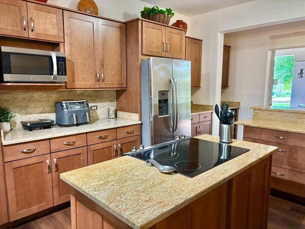 A kitchen features wood cabinets, granite countertops, a stainless steel refrigerator, and a center island — 22 FAIRWAYS VILLAGE DR, DORADO, PR
