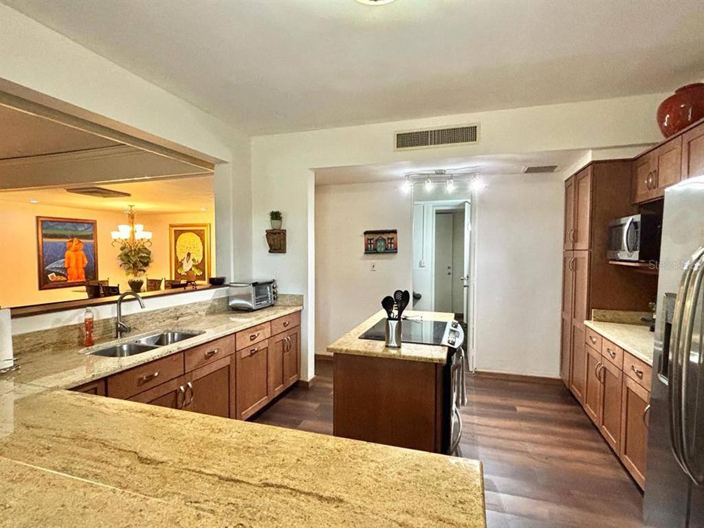 A kitchen features wood cabinets, granite countertops, a central island, and a pass-through window — 22 FAIRWAYS VILLAGE DR, DORADO, PR