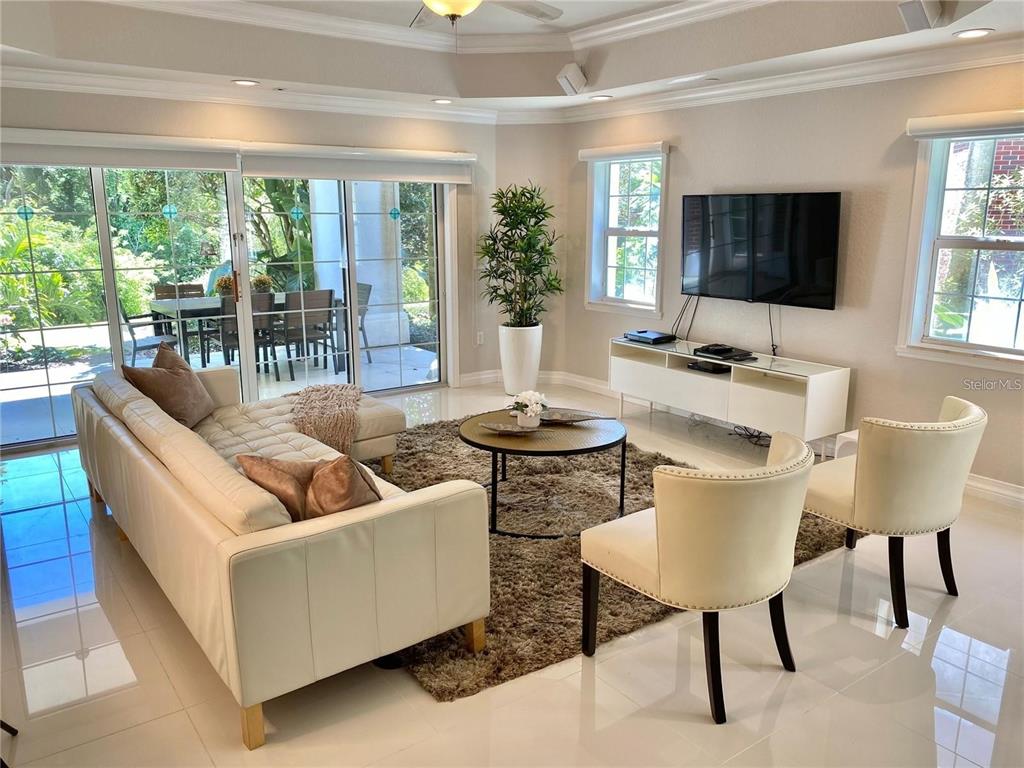 A living room features a white sofa, two cream chairs, a coffee table, and a television — 7652 WHISPER WAY UNIT 104, REUNION, FL