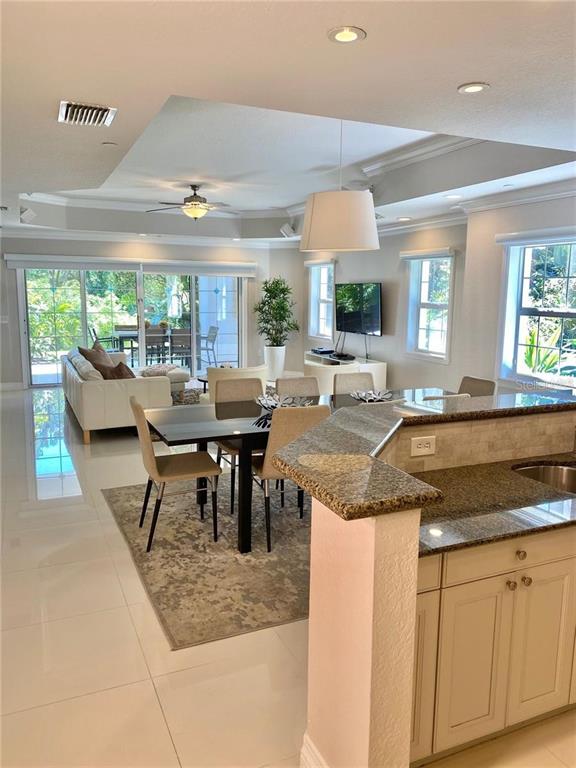 An open-concept living and dining area features tile floors, a kitchen island, and sliding doors — 7652 WHISPER WAY UNIT 104, REUNION, FL