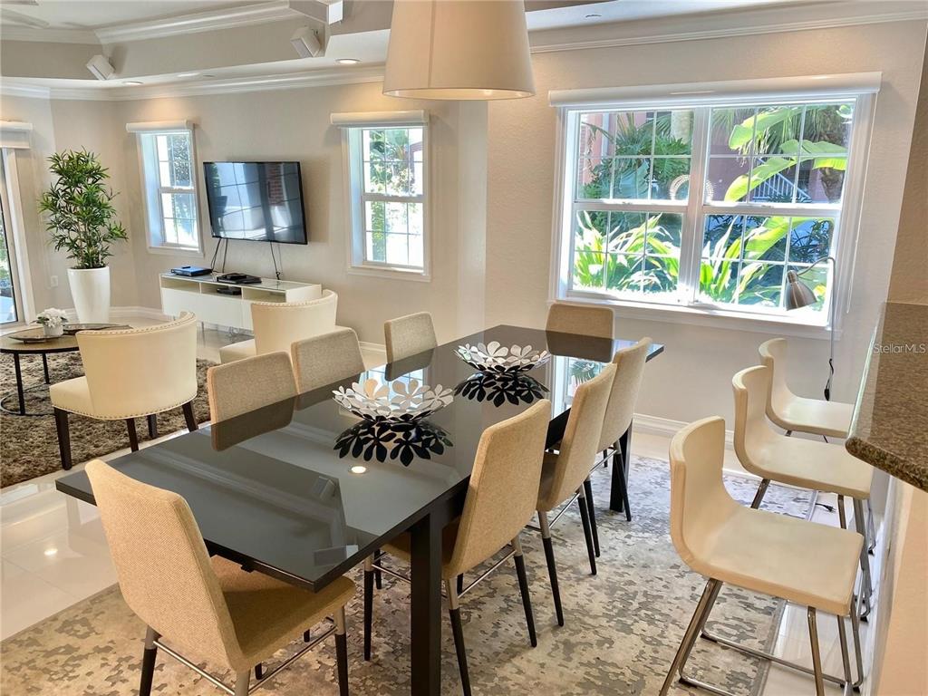 A dining area with a glass-topped table and chairs sits adjacent to a living room — 7652 WHISPER WAY UNIT 104, REUNION, FL
