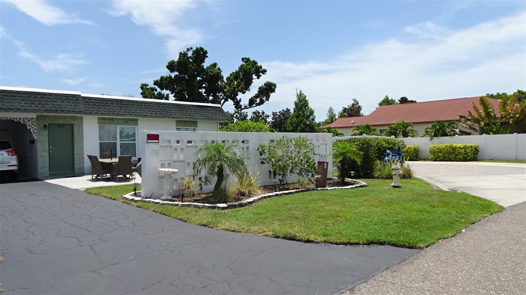 A single-story house with a white decorative privacy wall, a paved driveway, and landscaping — 7868 40TH AVENUE N UNIT 7868, ST PETERSBURG, FL