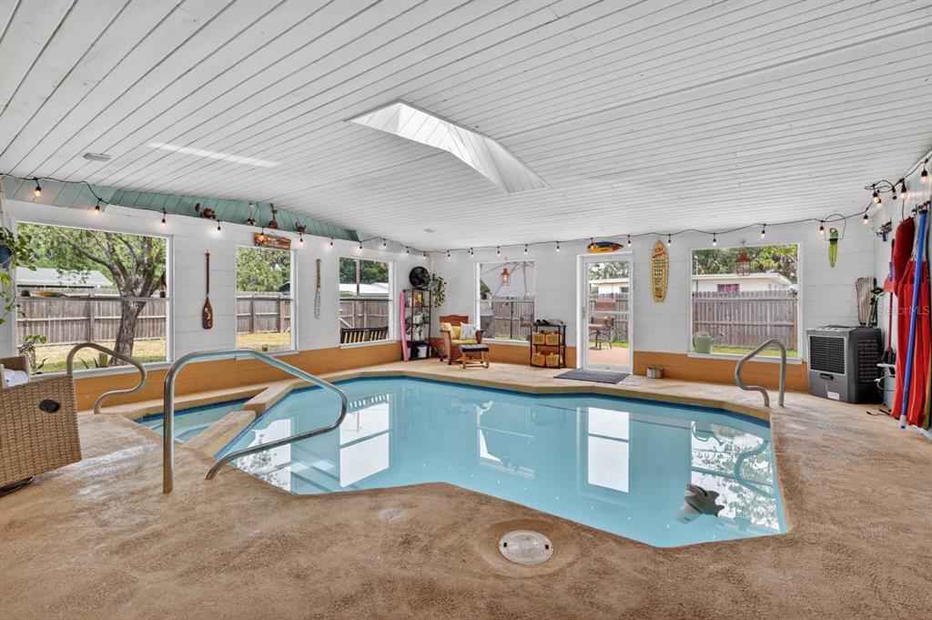 An indoor swimming pool room features a skylight, white paneled walls, and a textured floor — 925 FLAGLER AVENUE, EDGEWATER, FL
