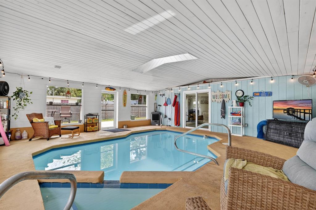 An indoor swimming pool room with a white wood-paneled ceiling, skylight, and wicker furniture — 925 FLAGLER AVENUE, EDGEWATER, FL