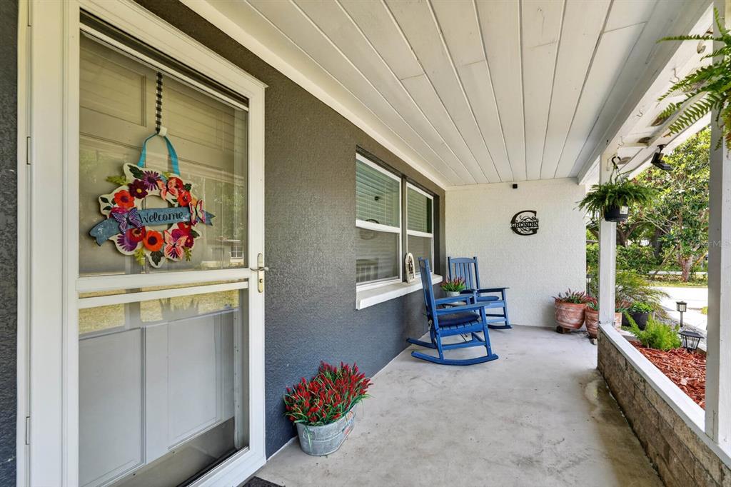 A covered front porch features a white door with a wreath, two blue rocking chairs, and potted plants — 925 FLAGLER AVENUE, EDGEWATER, FL