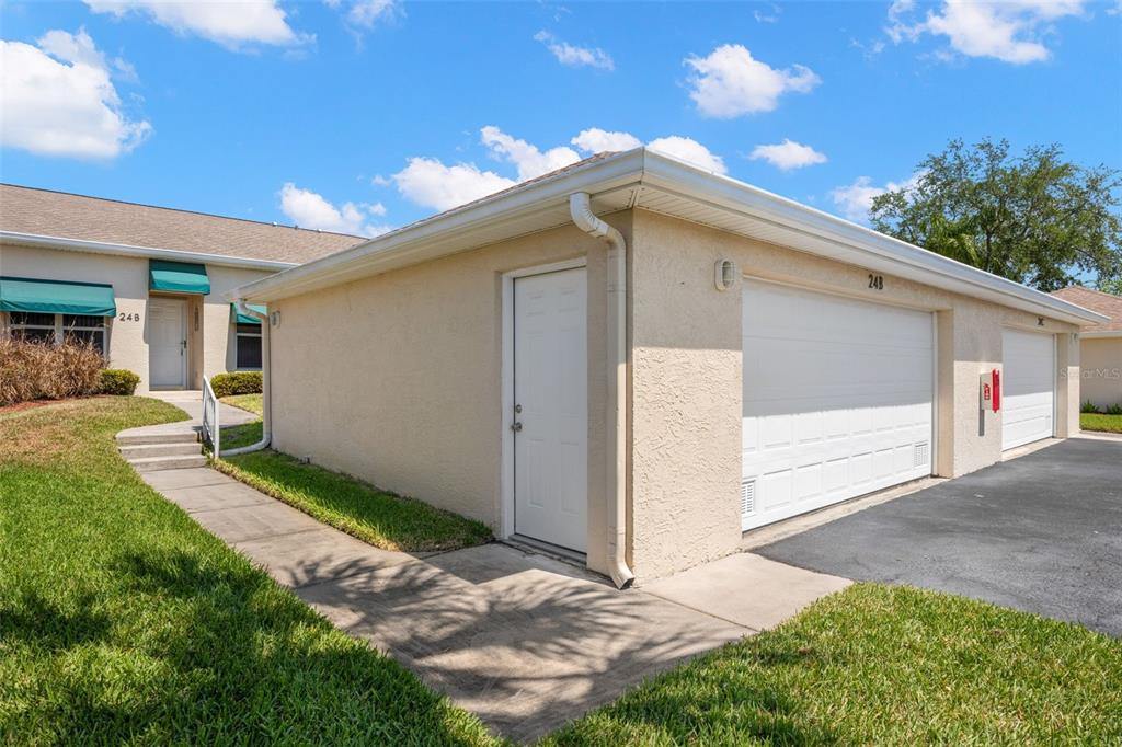A beige stucco garage building with a white door and a white sectional garage door — 6600 100TH WAY N UNIT 24B, ST PETERSBURG, FL