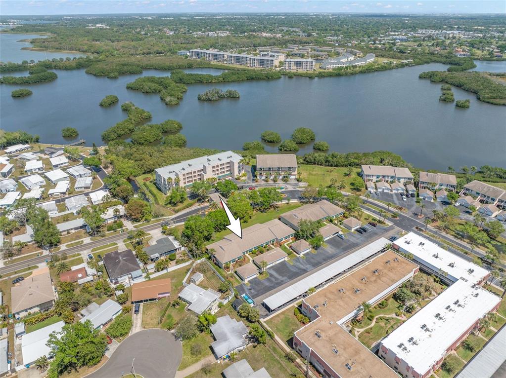 An aerial view shows a multi-unit residential building with a white arrow pointing toward it — 6600 100TH WAY N UNIT 24B, ST PETERSBURG, FL