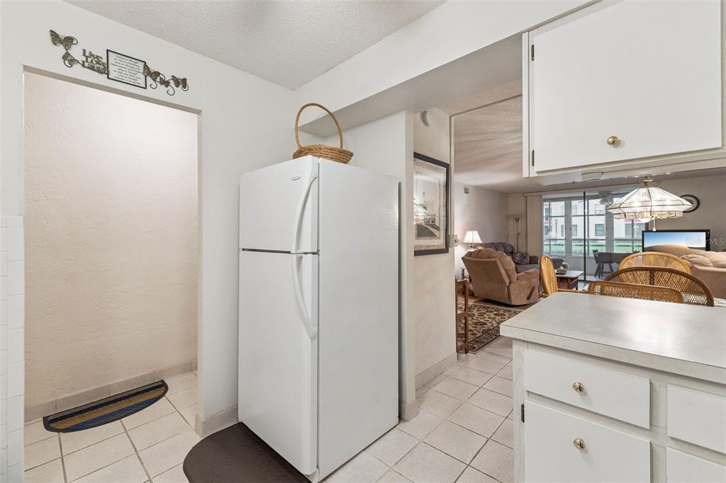 A white refrigerator stands in a tiled kitchen area adjacent to a living room — 325 WILDER BOULEVARD UNIT 103, DAYTONA BEACH, FL