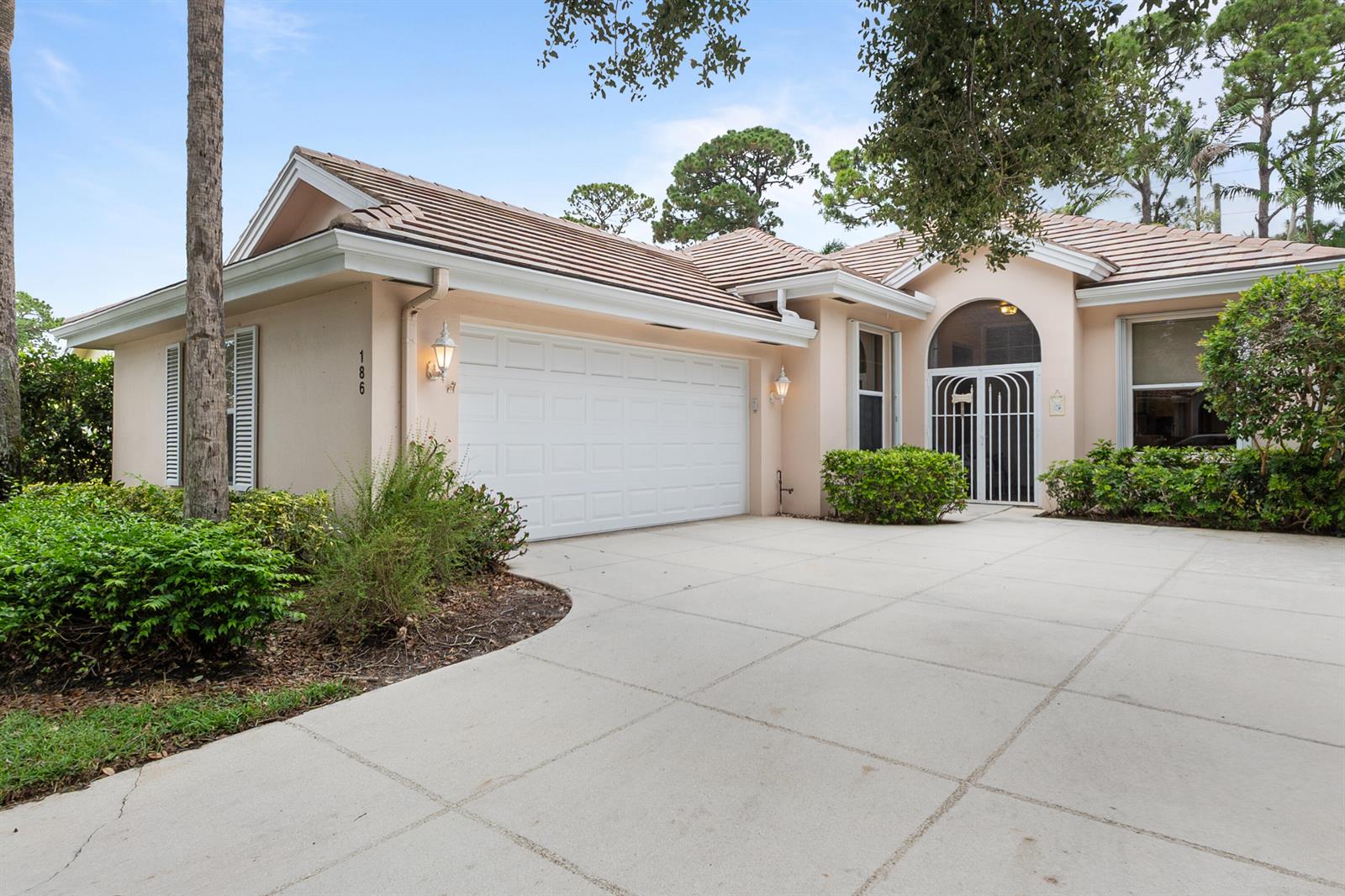A single-story house with a beige stucco exterior, a two-car garage, and a concrete driveway — 186 S Hampton Drive, Jupiter FL 33458, JUPITER, FL