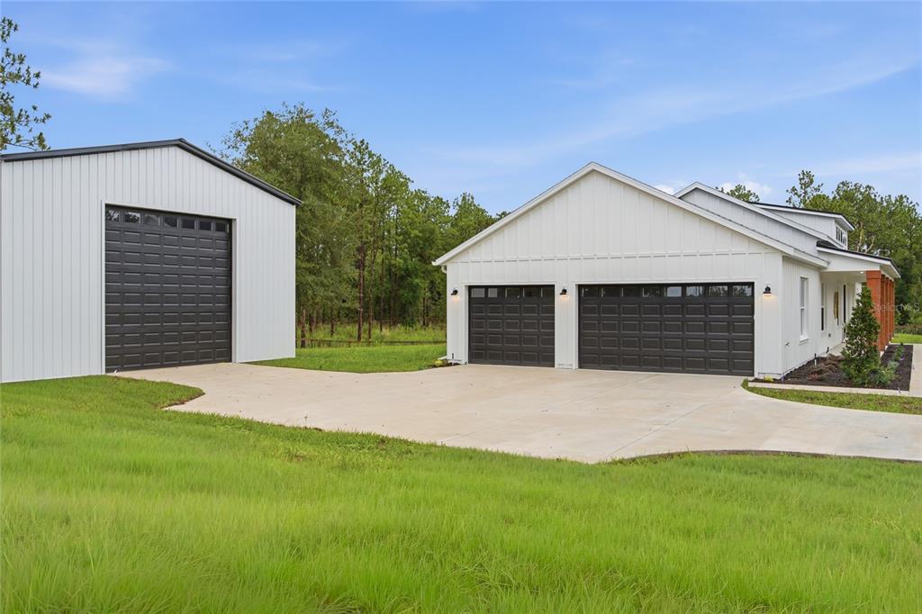 A white farmhouse with vertical siding and a covered porch featuring stained wooden support columns — 8730 NW 17TH CIRCLE, OCALA, FL
