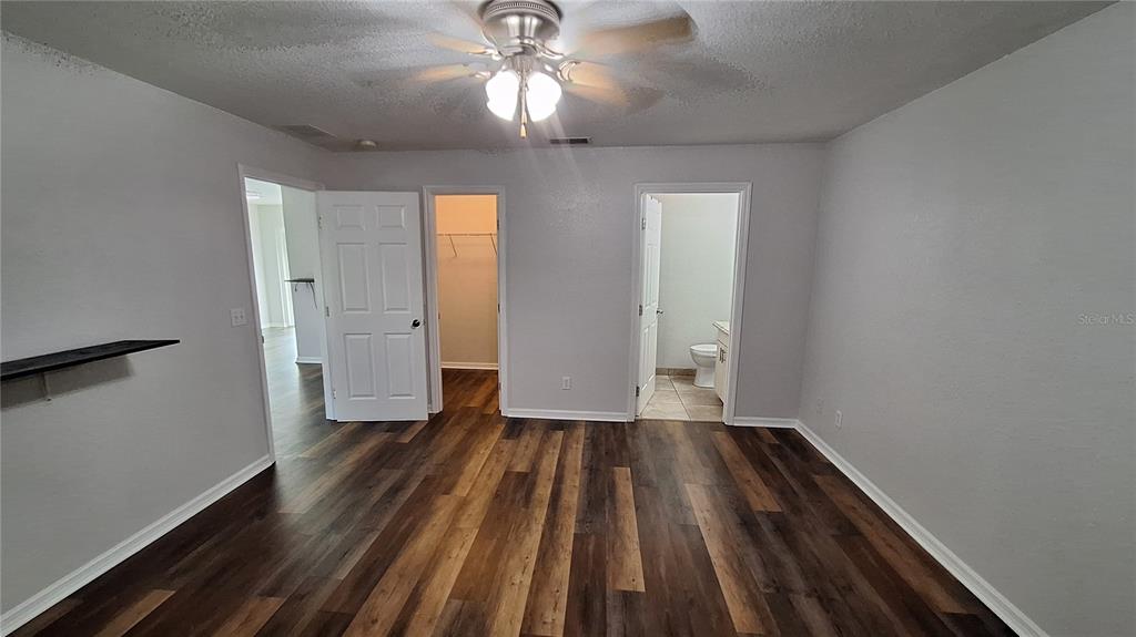 A bedroom with wood-look flooring, a ceiling fan, a closet, and an attached bathroom — 80 PECAN PASS, OCALA, FL